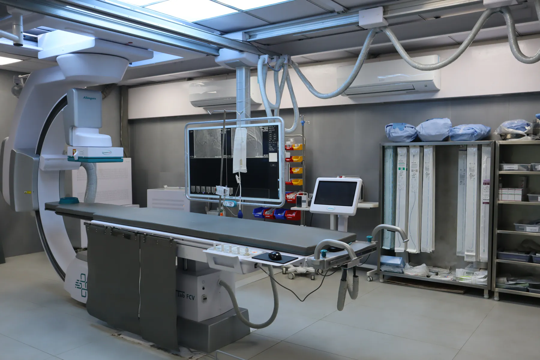 Interventional cardiology procedure room with angiography table and monitors at Apaxis Hospitals